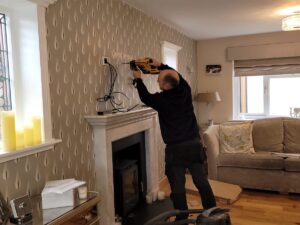 Technician wall mounting a flat-screen TV in a living room.